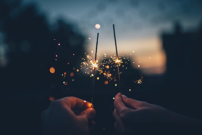 Two hands holding sparklers at evening